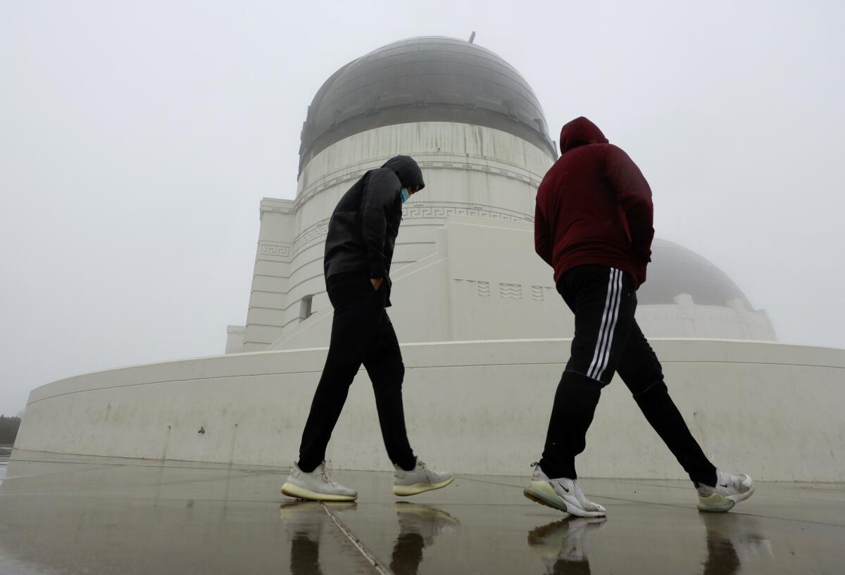 Tessie Edwards, left, and Eddie Medina brave the rain to visit Griffith Observatory in Griffith Park.