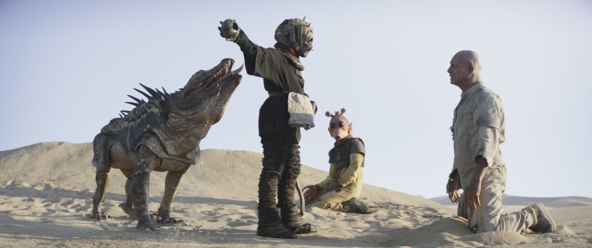 a reptile and three humanoids in a desert