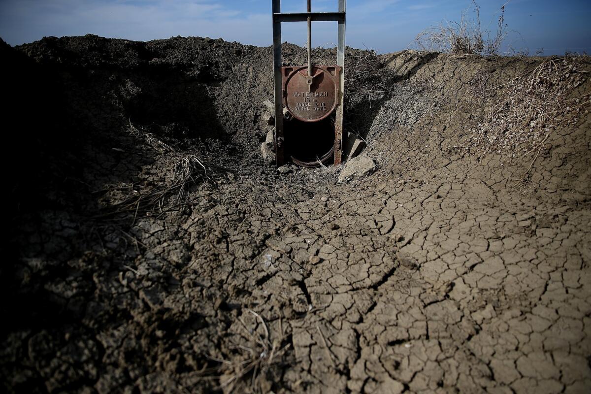 Dried and cracked earth is visible in an irrigation channel near Firebaugh, Calif.