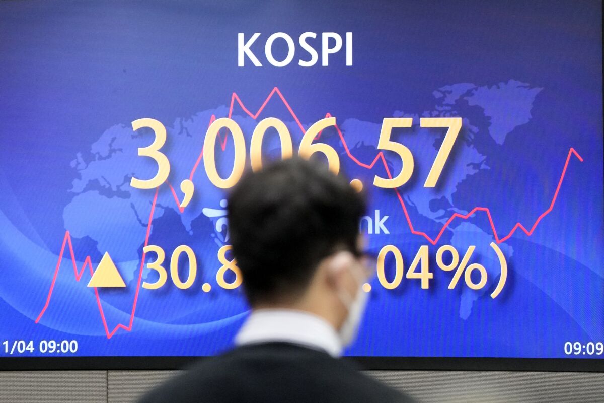 A currency trader walks by the screen showing the Korea Composite Stock Price Index (KOSPI) at a foreign exchange dealing room in Seoul, South Korea, Thursday, Nov. 4, 2021. Asian shares rose Thursday, boosted by the announcement from the U.S. Federal Reserve on winding down the extraordinary aid for the economy it been providing since the early days of the pandemic.(AP Photo/Lee Jin-man)