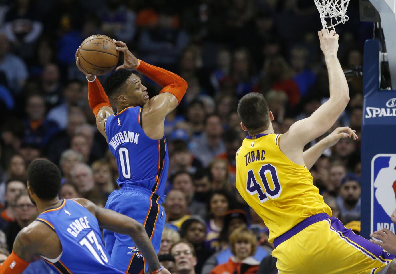 Oklahoma City Thunder guard Russell Westbrook (0) grabs a rebound between teammate Paul George (13) and Los Angeles Lakers center Ivica Zubac (40) during an NBA basketball game between the Los Angeles Lakers and the Oklahoma City Thunder in Oklahoma City, Thursday, Jan. 17, 2019. (AP Photo/Sue Ogrocki)