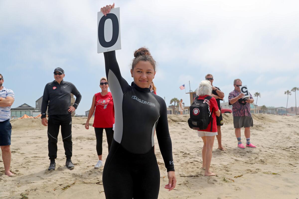 Josie Stuard holds up a score for her husband Grant, Mr. Irrelevant, after he wiped out during surfing lessons.