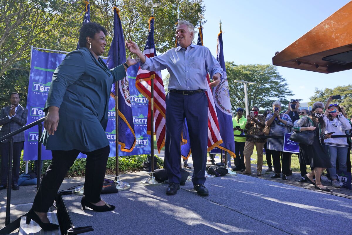 Voting rights activist Stacey Abrams, left, arrives on stage during a rally with Democratic gubernatorial candidate, former Virginia Gov. Terry McAuliffe in Norfolk, Va., Sunday, Oct. 17, 2021. Abrams was in town to encourage voters to vote for the Democratic gubernatorial candidate in the November election. (AP Photo/Steve Helber)