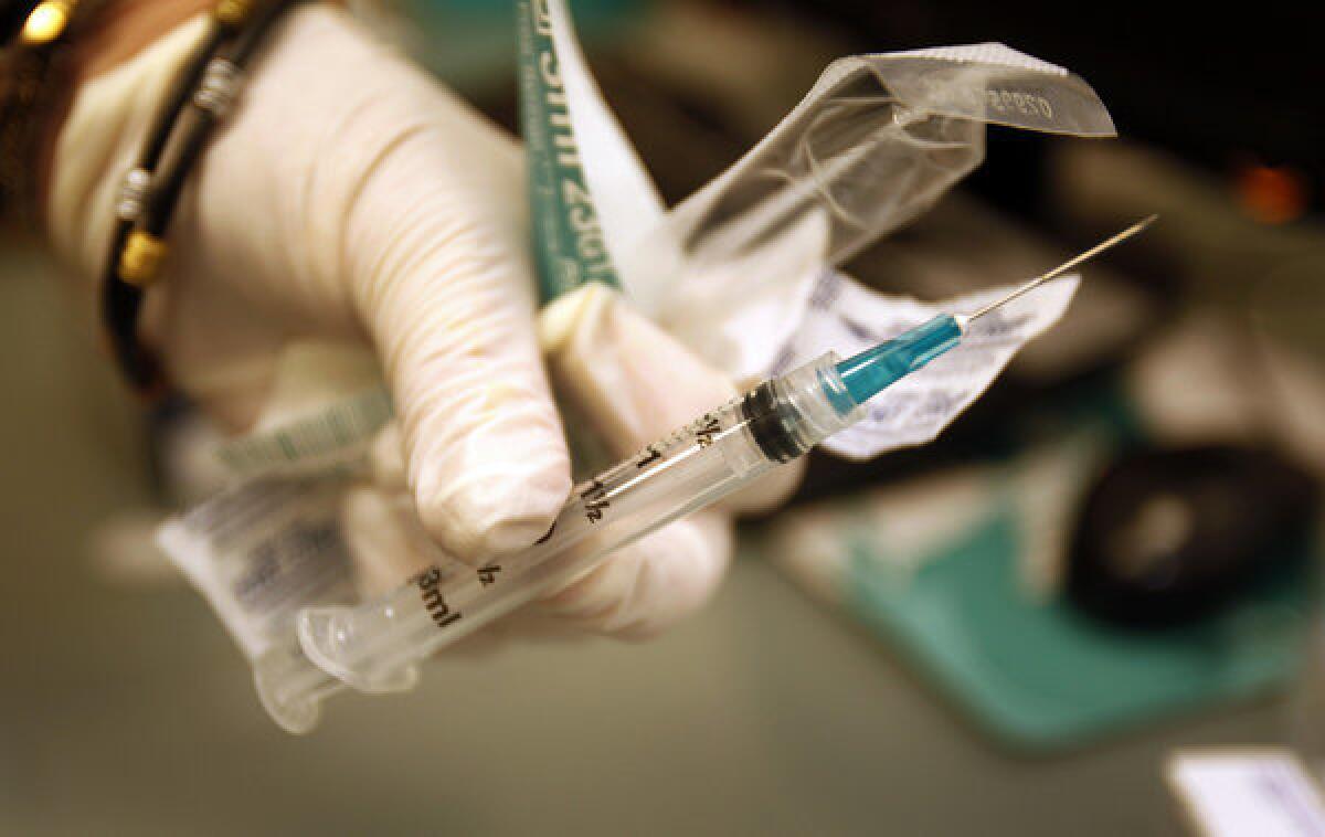A nurse holds a syringe of meningitis vaccine at an AIDS Healthcare Foundation pharmacy.