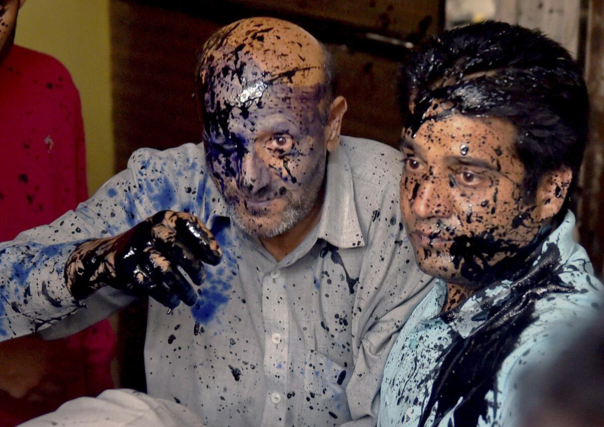 Jammu and Kashmir lawmaker Abdul Rashid Sheikh, left, after suspected activists of a right-wing organization threw ink on his face after he addressed a press conference in New Delhi to protest the death of a Muslim trucker killed over a rumor that he was transporting beef.