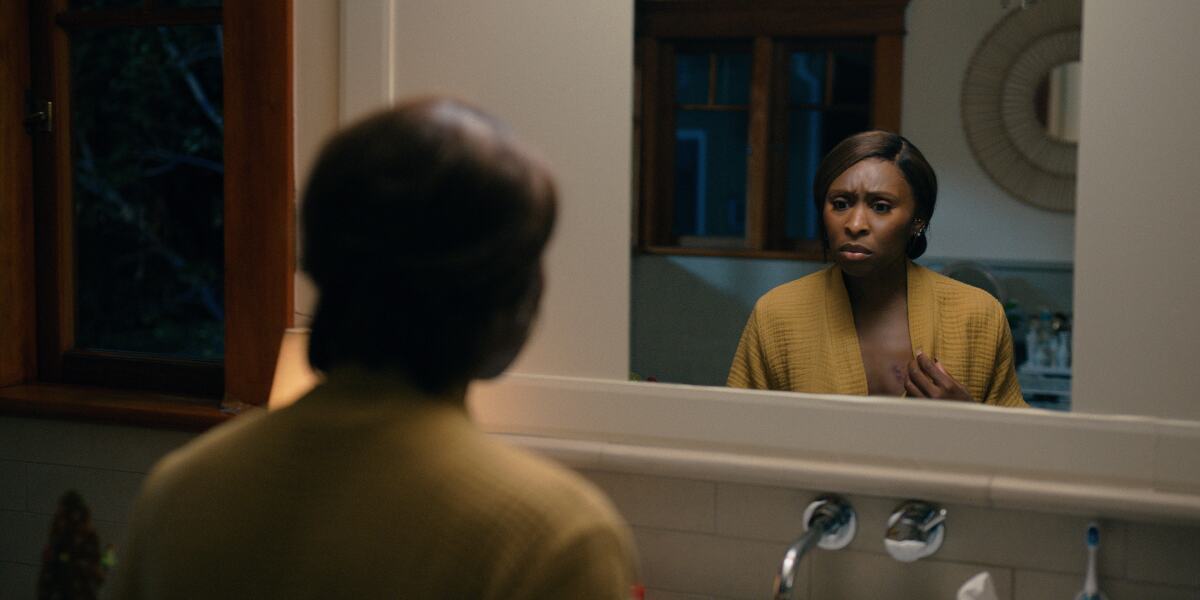 A woman examines bite marks on her chest in the mirror