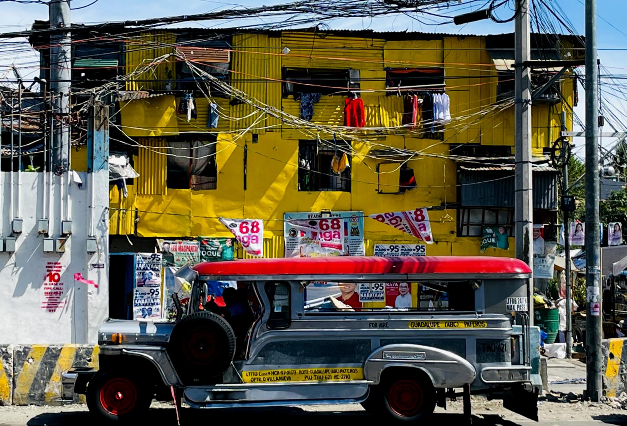 A jeepney in front of a yellow building.