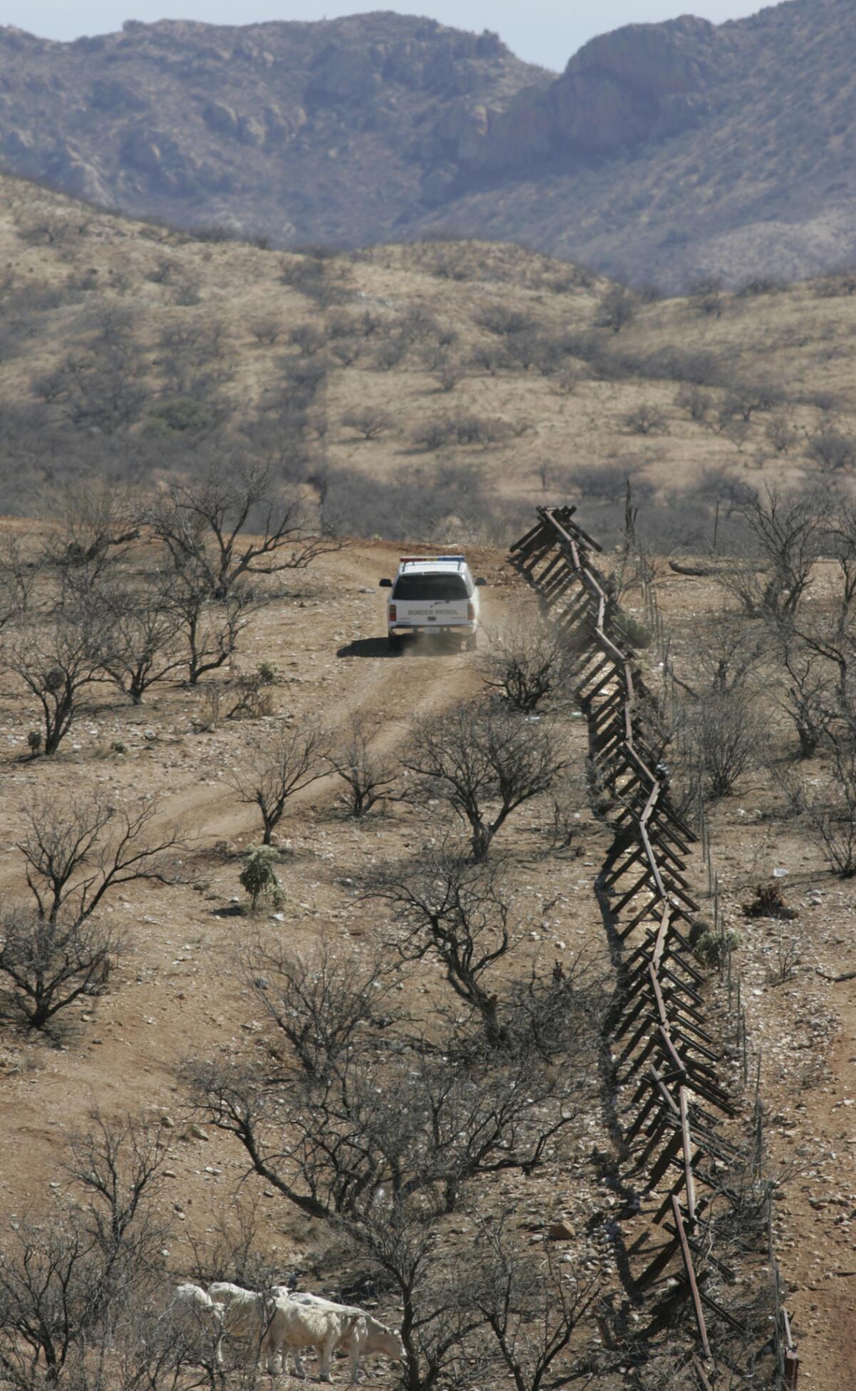 Feb. 28, 2007: A U.S. Border Patrol agent follows a vehicle barrier that defines the border to about four miles east of Sasabe, Ariz. Farther east there is no border barrier, but agents observe the remote desert area with aerial drones and ground sensors.