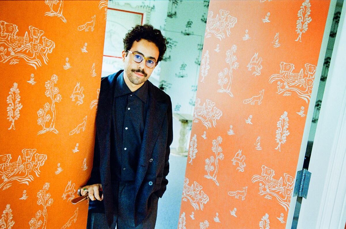Ramy Youssef leans against a bright, patterned door for a portrait.