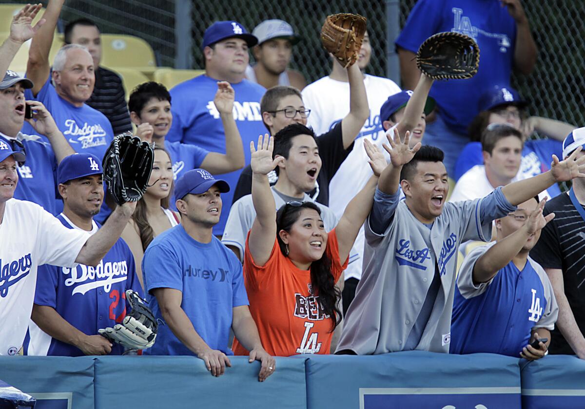 A Giants fan wearing an orange "Beat LA" T-shirt joins a crowd of Dodgers fans in left field trying to catch balls hit during batting practice at Chavez Ravine.