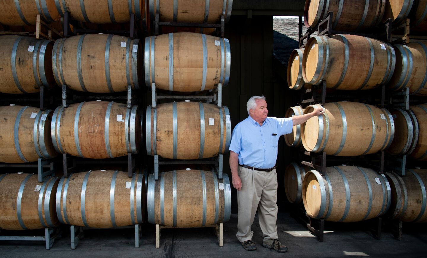 Hank Wetzel stands between stacks of stored barrels of wine at Alexander Valley Vineyards. Wetzel says he voted for President Trump because “he was a businessman… But in the short term, these tariffs are not working.”