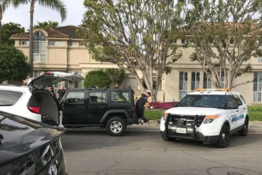 A police vehicle is parked Monday outside a Newport Beach apartment where a man and a woman were found dead the night before. The apartment complex is in the 2100 block of East 15th Street. (Julia Sclafani / Daily Pilot)