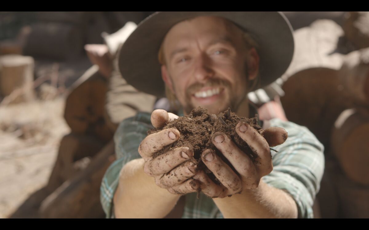 A farmer holds a handful of dirt in the documentary "Kiss the Ground."