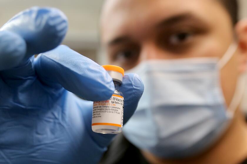 LYNWOOD, CALIF. - MAR. 16, 2022. Nurse Luis Garcia holds a vial of the Pfizer vaccine as he mixes up childrens doses to be used for kids at Hellen Keller Elementary School in Lynwood on Wednesday, Mar. 16, 2022. (Luis Sinco / Los Angeles Times)