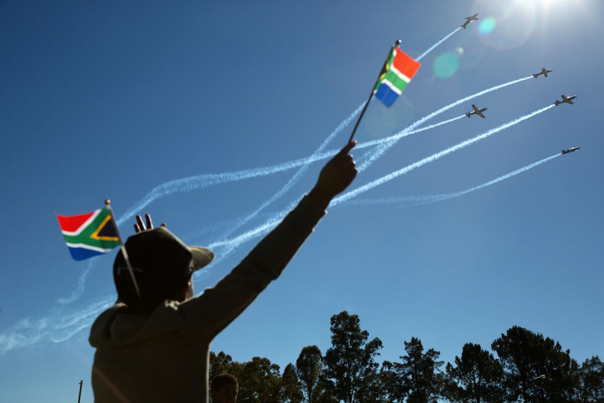 A boy waves a flag as members of the South African Air Force Silver Falcons fly over the Freedom Day event.