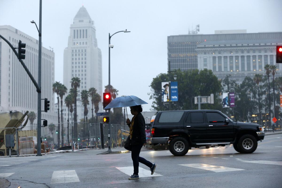 A pedestrian walks along a street in downtown Los Angeles during a rainy Oct. 17 morning.