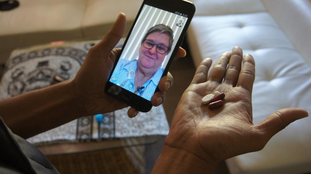 A nurse, seen on the phone screen, uses Skype to remotely monitor a patient taking antibiotics.
