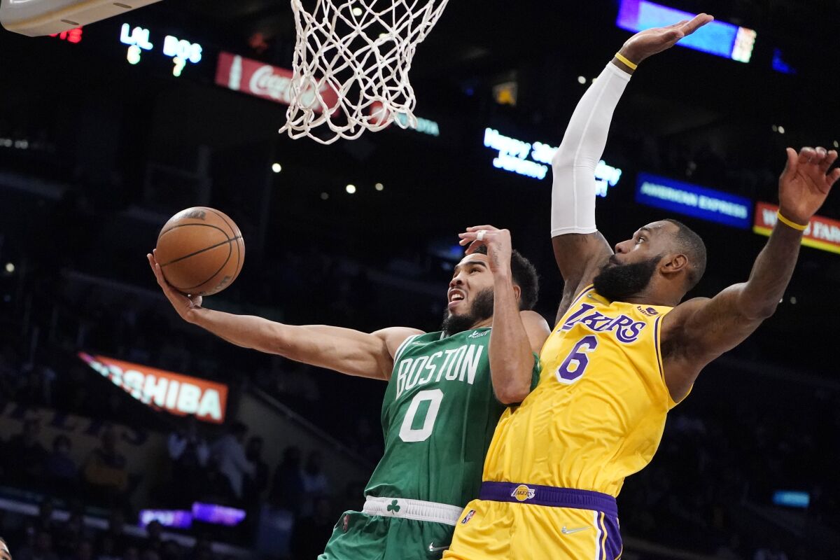 Boston Celtics forward Jayson Tatum (0) drives to the basket while Los Angeles Lakers forward LeBron James (6) defends during the first half of an NBA basketball game Tuesday, Dec. 7, 2021, in Los Angeles. (AP Photo/Marcio Jose Sanchez)