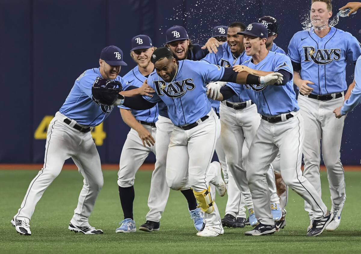 Tampa Bay Rays teammates celebrate with Yandy Diaz, center, after Randy Arozarena scored from third base on Diaz's fielder's choice to Cleveland Indians second baseman Cesar Hernandez during the ninth inning of a baseball game Monday, July 5, 2021, in St. Petersburg, Fla. (AP Photo/Steve Nesius)