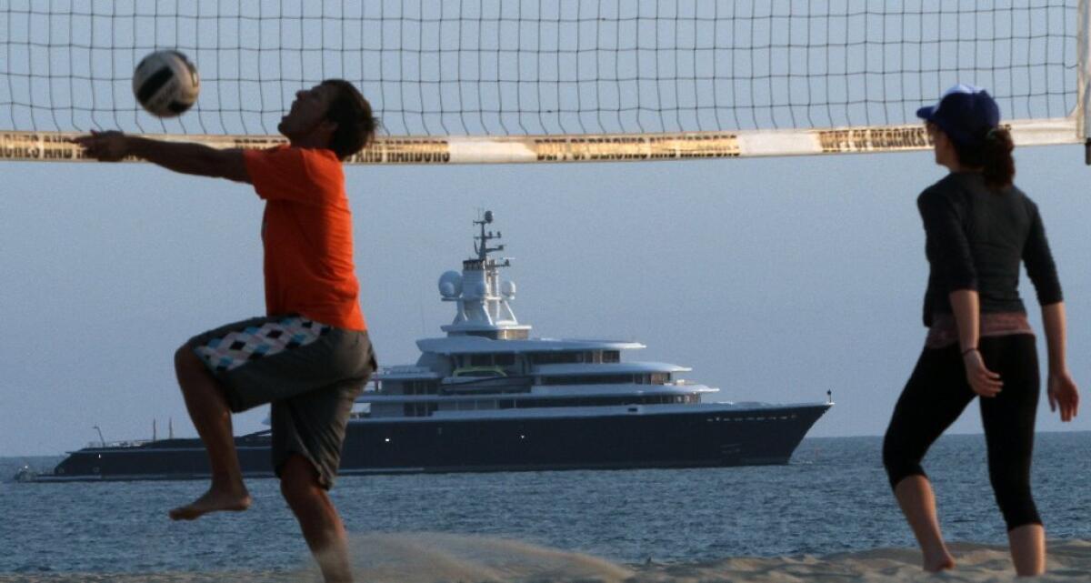 Mark Gelazela goes for a ball as Sara Safadi backs him up as they play volleyball at Venice Beach. In the distance, the 377-foot-long mega-yacht the Luna, owned by Russian billionaire Roman Abramovich, sits off the beach just north of the Marina del Rey harbor entrance on Tuesday.