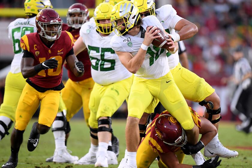 LOS ANGELES, CALIFORNIA - NOVEMBER 02: Justin Herbert #10 of the Oregon Ducks is held by Jay Tufele #78 of the USC Trojans and eventually sacked during the first half at Los Angeles Memorial Coliseum on November 02, 2019 in Los Angeles, California. (Photo by Harry How/Getty Images)