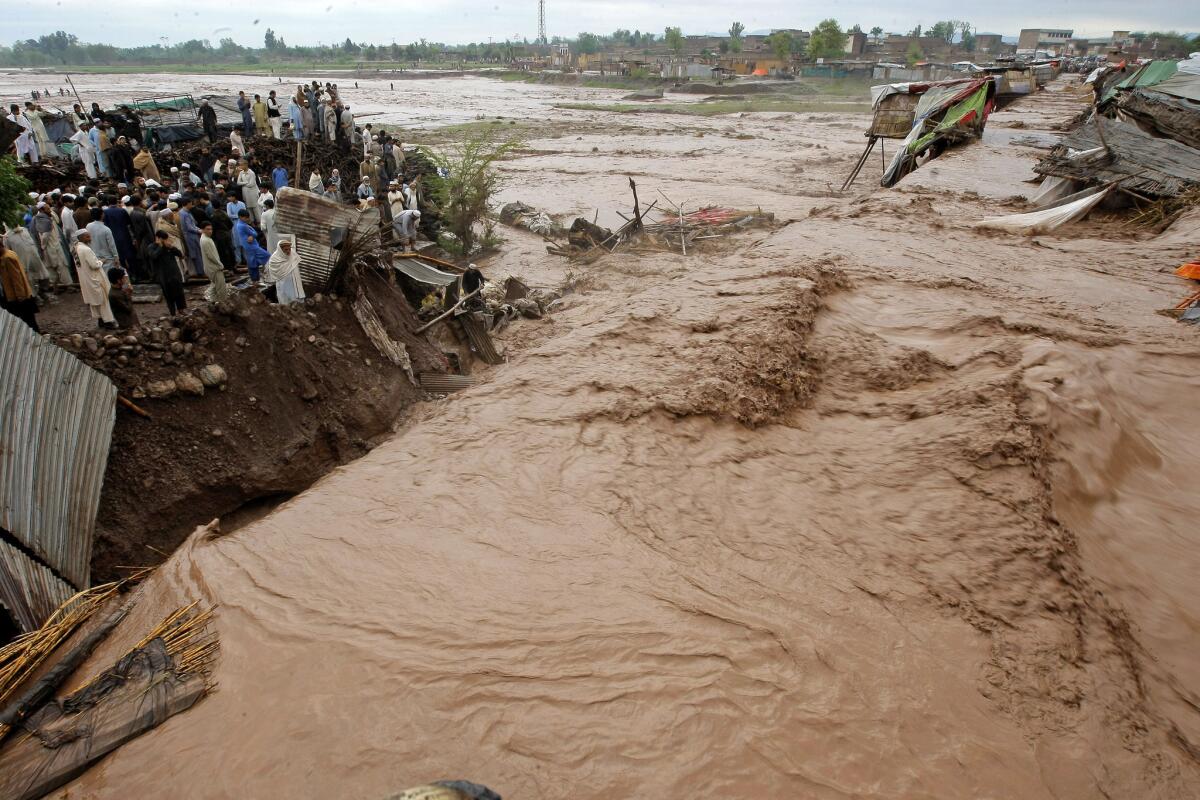 Villagers watch water rush in during a flash flood. (Mohammad Sajjad / Associated Press)