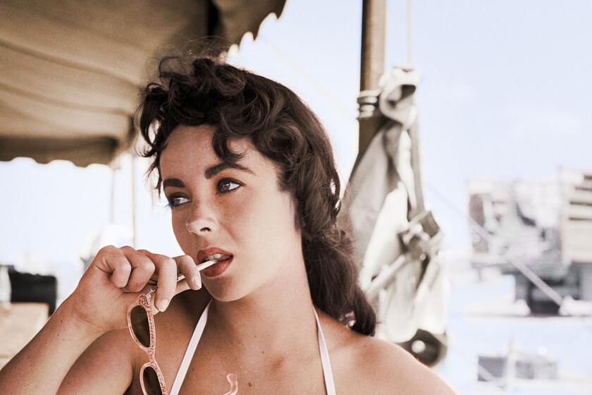 This iconic and elegant portrait captured by celebrity photographer Frank Worth features actress Elizabeth Taylor on the set of the film "Giant" for her role as character Leslie Benedict. This half-length shot features the actress in a white bikini top posed holding her sunglasses touching the tip of them to her mouth. Giant is a 1956 American epic Western drama film about sprawling epic covering the life of a Texas cattle rancher and his family and associates. Directed by George Stevens from a screenplay adapted by Fred Guiol and Ivan Moffat from Edna Ferber's 1952 novel. The film stars Elizabeth Taylor, Rock Hudson, James Dean, and features Carroll Baker Jane Withers Chill Wills Mercedes McCambridge, Dennis Hopper, Sal Mineo, Rod Taylor, Elsa Cardena,s and Earl Holliman.