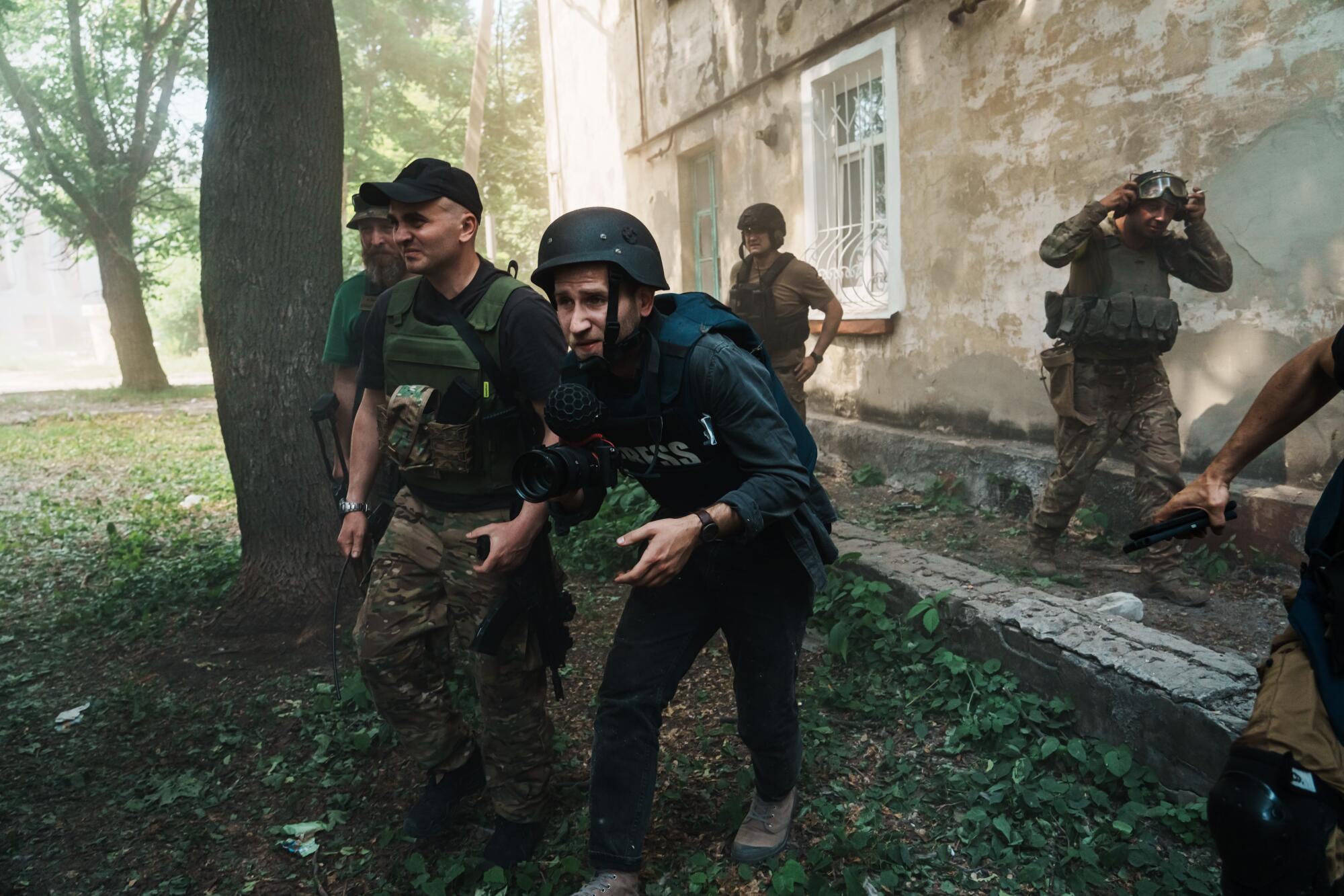 Soldiers and journalists flee for cover after a bombardment hit nearby, sending dust in the air, in Lysychansk, Ukraine.