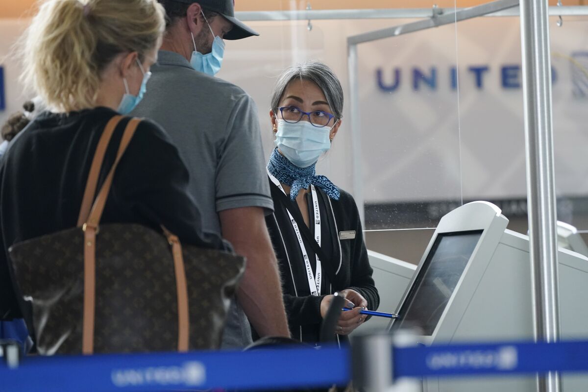 Travellers check in at a United Airlines kiosk with help from a United employee in the main terminal of Denver International Airport Thursday, Oct. 1, 2020, in Denver. (AP Photo/David Zalubowski)
