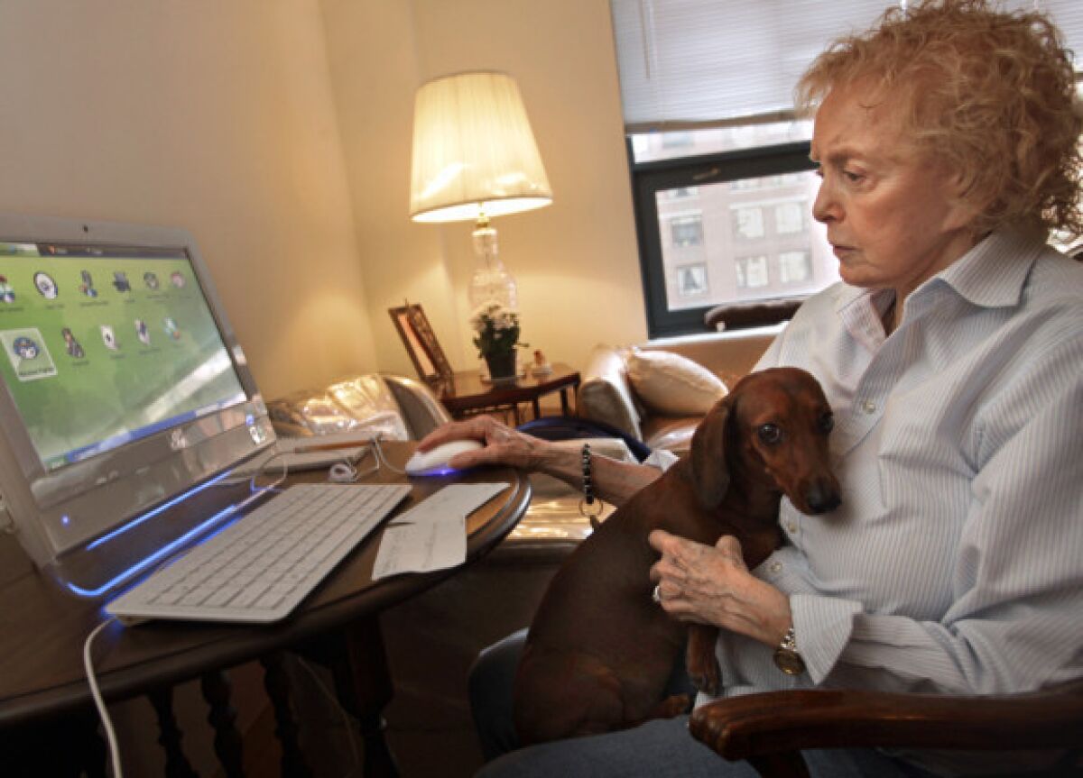 Rosemary Nickola works on her computer with her dog, Delilah, on her lap in her New York apartment in February. At that time, Nickola was struggling with technology, but this week she earned a certificate after completing a computer course.