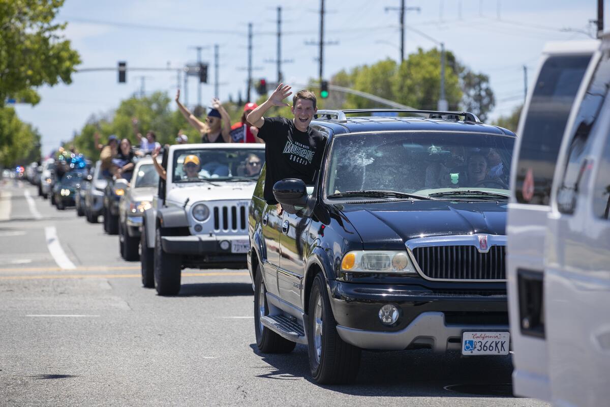 Students drive by Costa Mesa High School during a senior graduation parade.