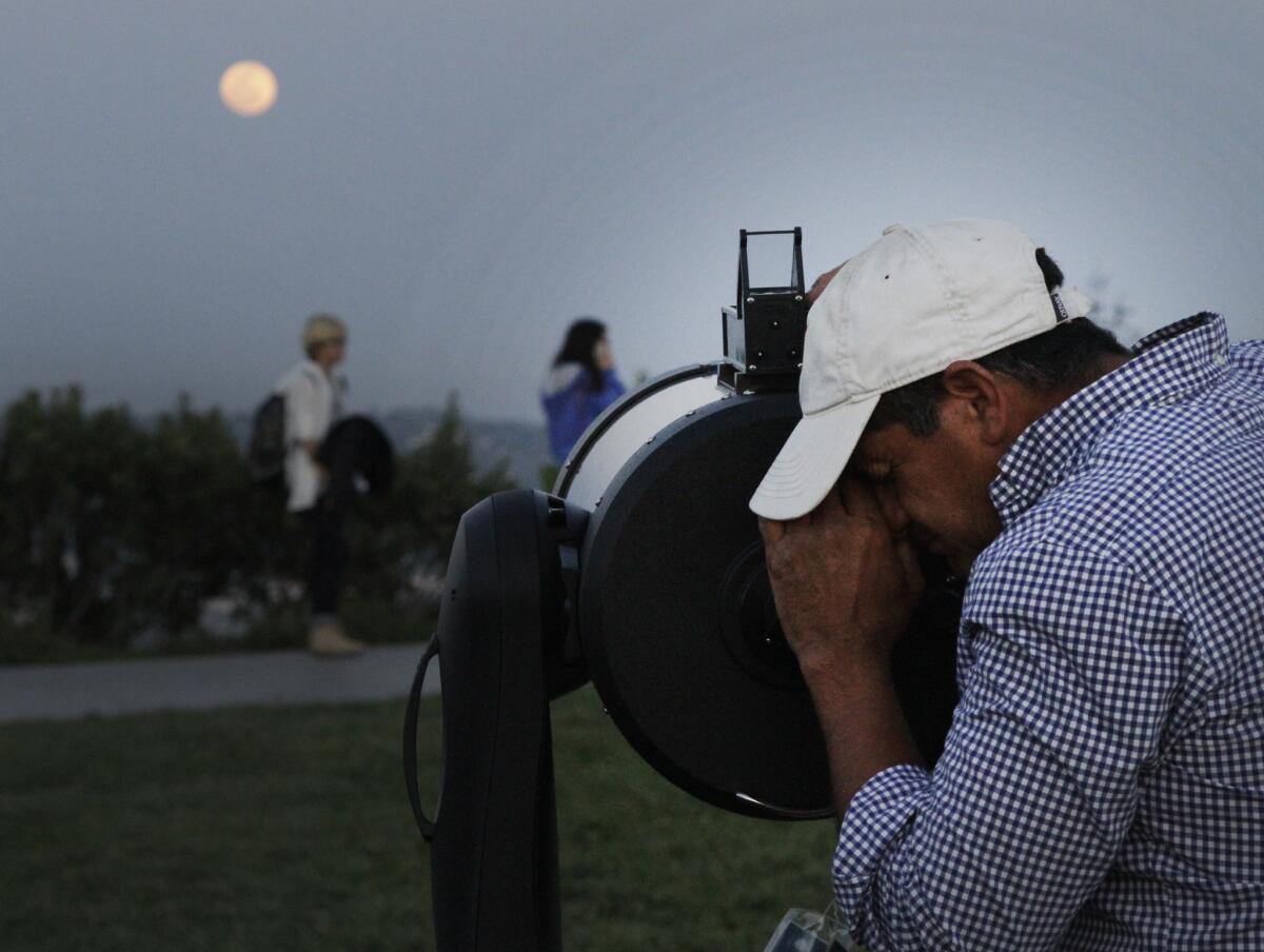 Richard Fuentes looking at the rising moon as people gathering at the Griffith Observatory for the lunar eclipse viewing event one year ago
