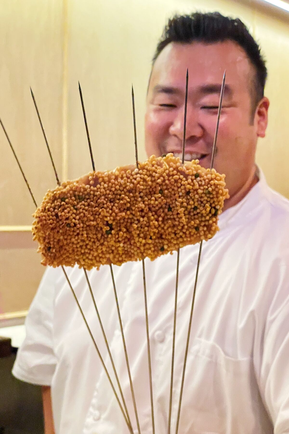 Chef-owner Daniel Son holds a piece of grilled fish that's been coated in puffy rice crackers at Sushi Sonagi in Gardena