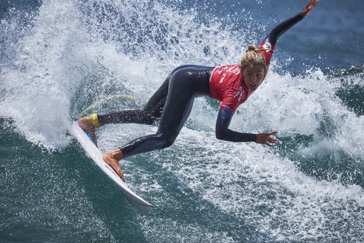 A woman on a surfboard slices across a wave.