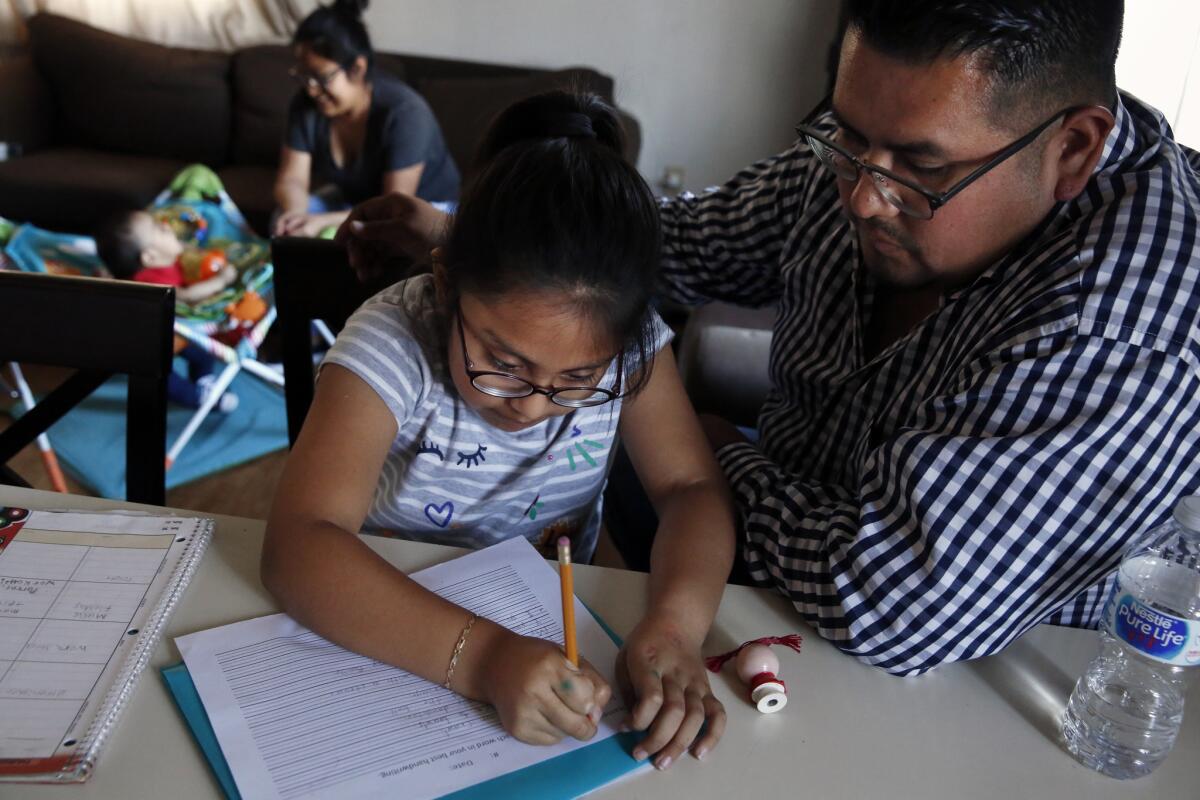 After dinner, Irie Mazas does her homework with the help of her father, Miguel Mazas. (Dania Maxwell / Los Angeles Times)