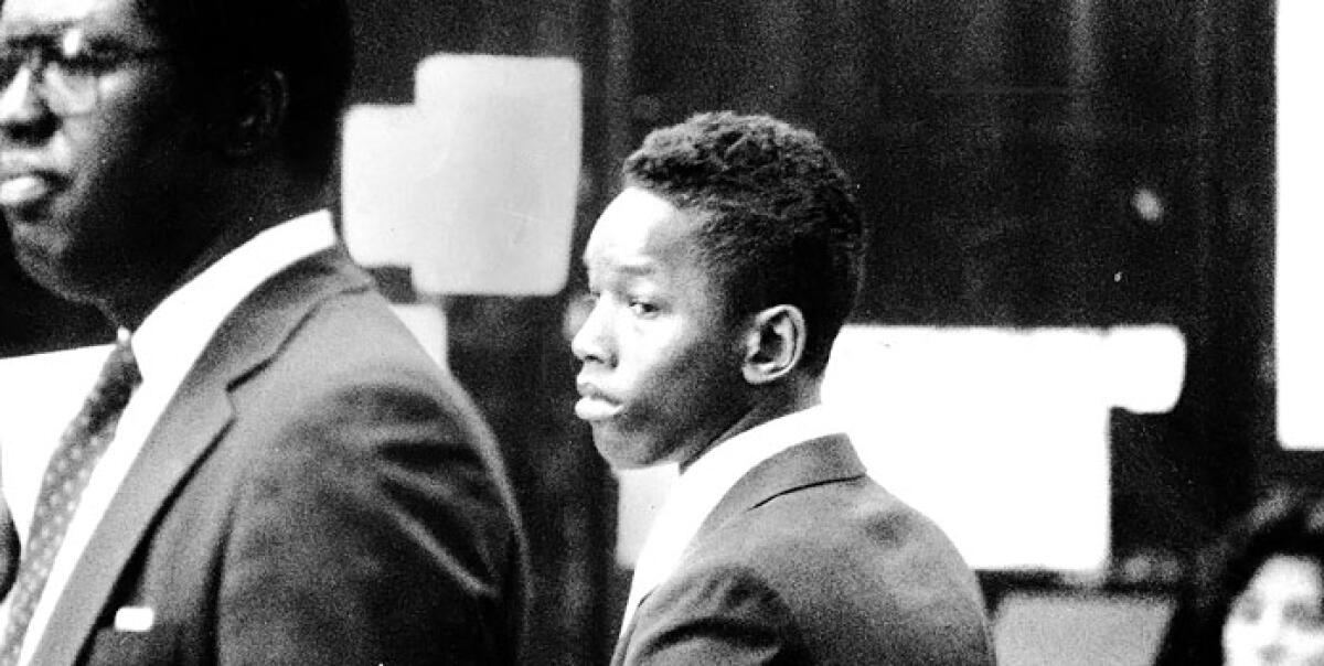 A black-and-white image of a young man and his lawyer in court