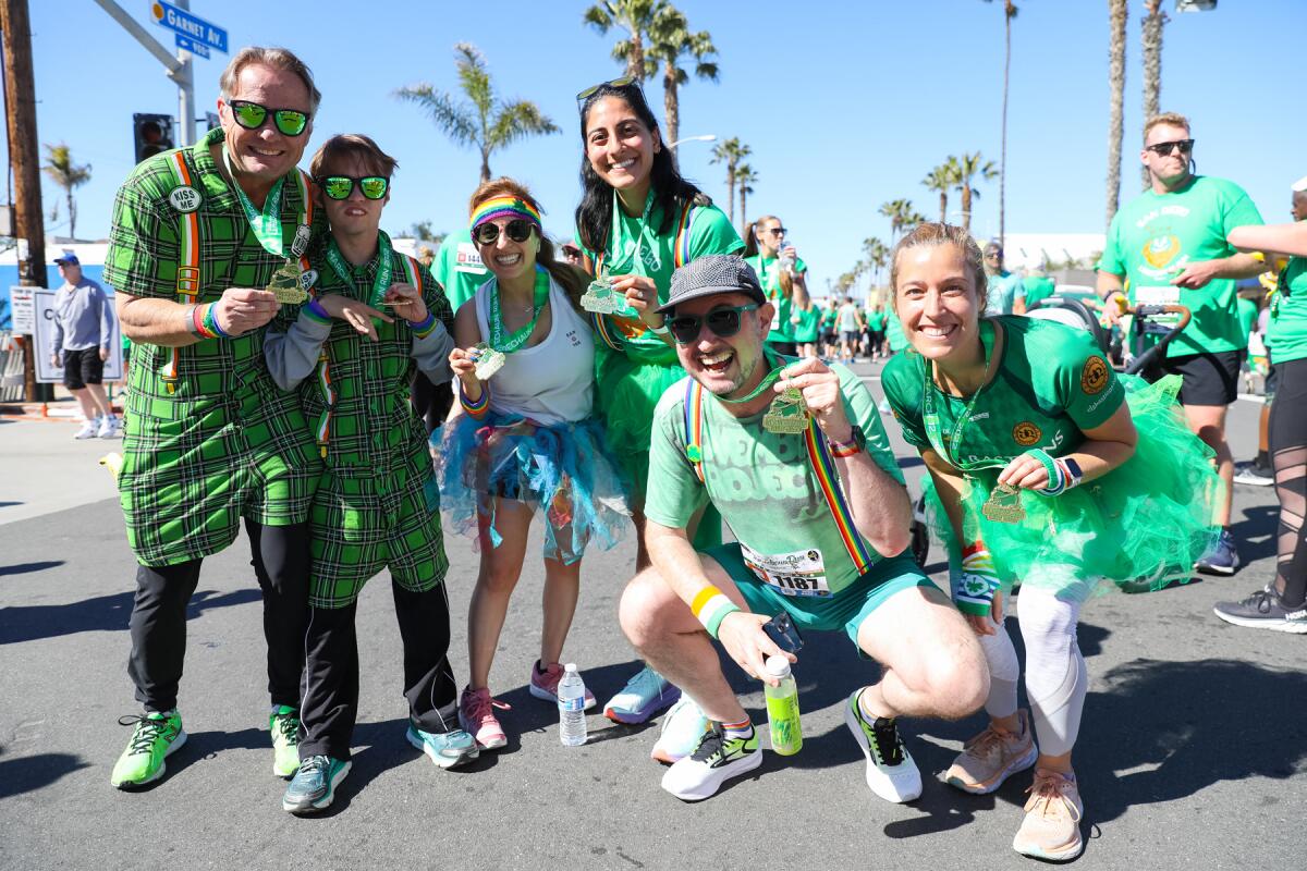 Leprechaun Run participants holding up their medals at the finish line.