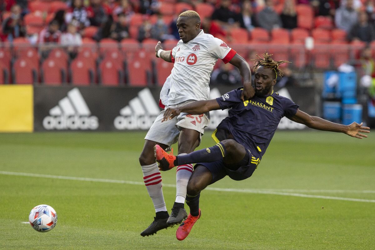 Toronto FC's Chris Mavinga, left, fends off Nashville's C.J. Sapong during the first half of an MLS soccer match, in Toronto, Sunday, Aug. 1, 2021. (Chris Young/The Canadian Press via AP)