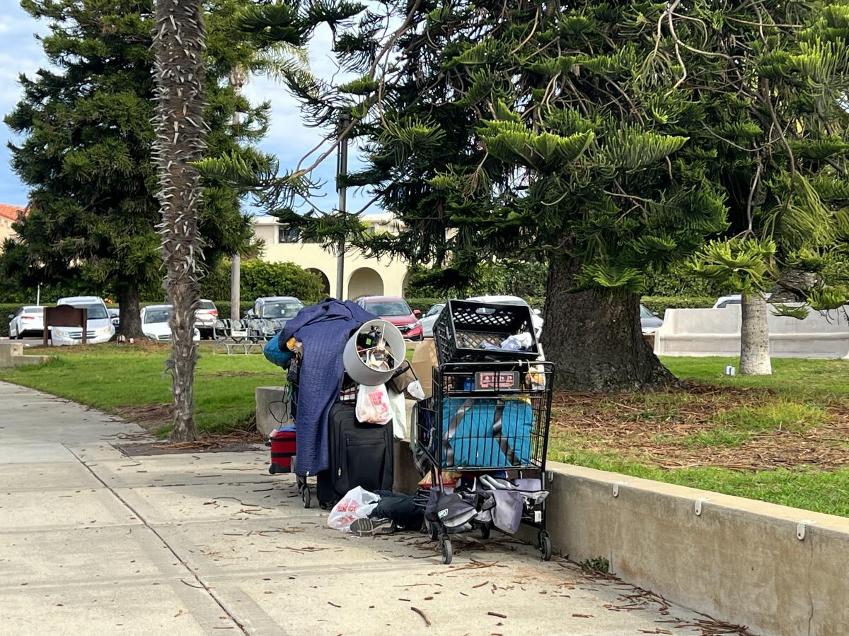 A homeless person sits among his belongings outside the La Jolla Recreation Center.