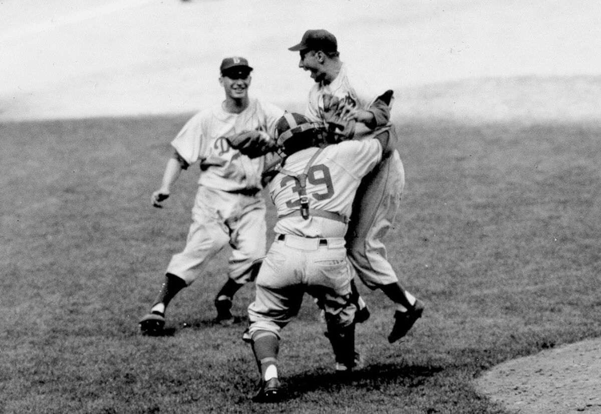 Brooklyn Dodgers pitcher Johnny Podres is lifted by catcher Roy Campanella after the final out of Game 7.