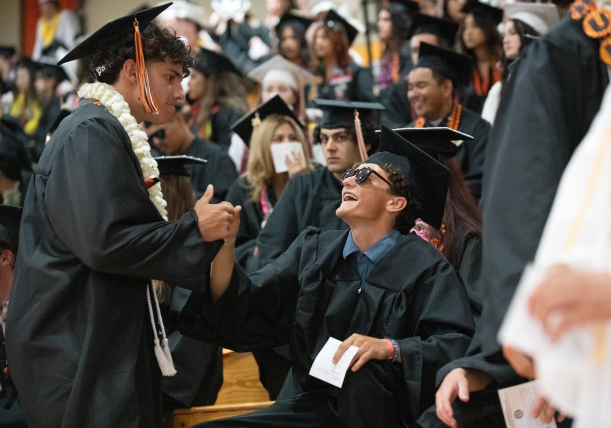 Kai Staley shakes hands with fellow seniors before walking to their commencement ceremony at Huntington Beach High.