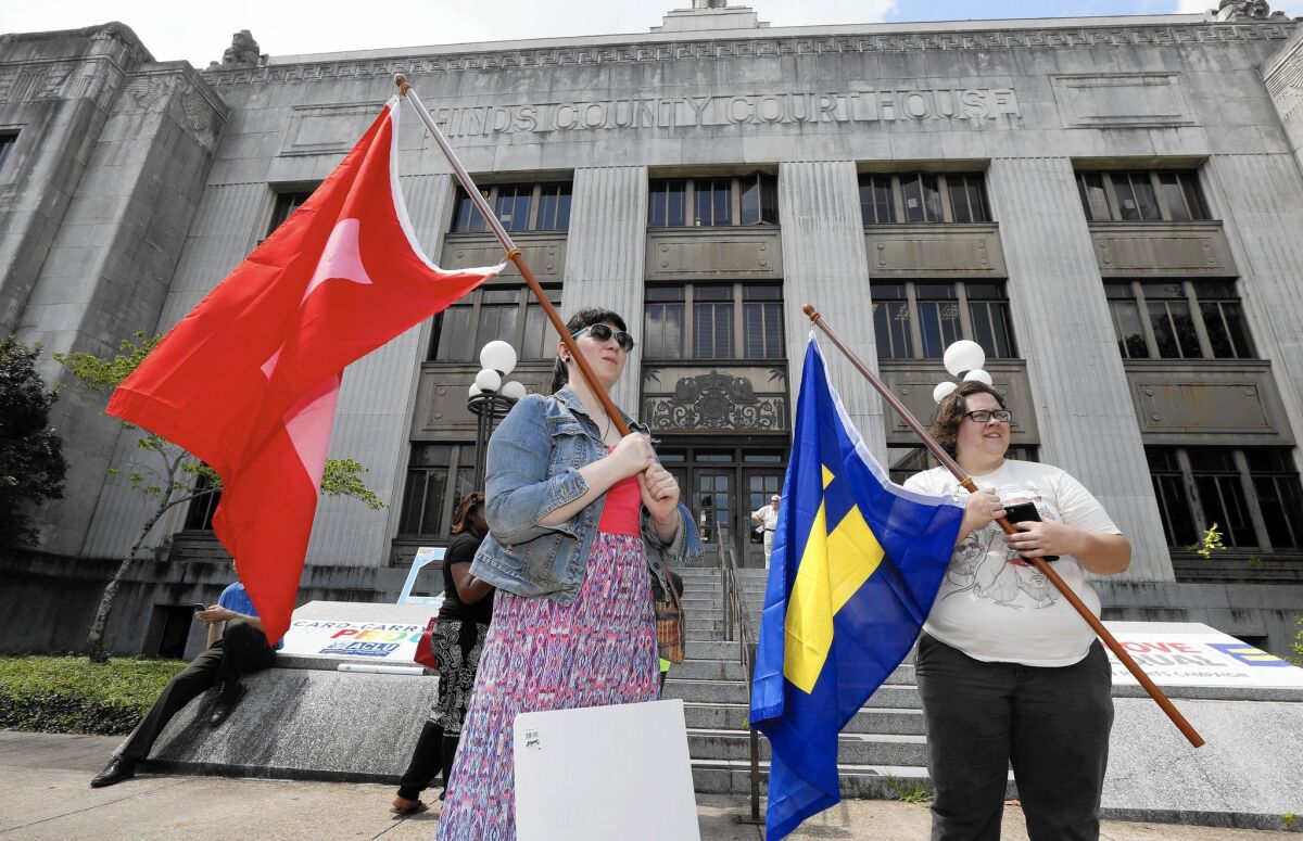 Engaged couple Karen Welch, left, and Brittany Raymond, both of Brandon, Miss., wave equality flags outside the Hinds County Courthouse in Jackson, Miss., on June 26 after Mississippi Atty. Gen. Jim Hood ordered court clerks not to issue marriage licenses to same-sex couples.