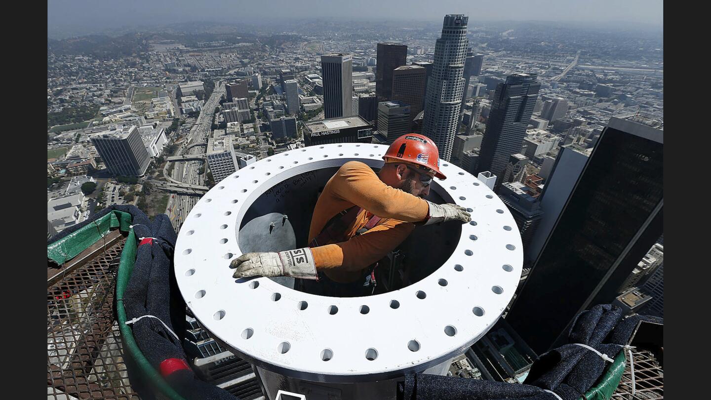Ironworker Eric Madrigal makes preparations for the final section of a 295-foot-long spire that when bolted in place will be 1,100 feet above the ground, making the Wilshire Grand in downtown L.A. the tallest building in the western United States. The skyscraper is at Wilshire Boulevard and Figueroa Street.