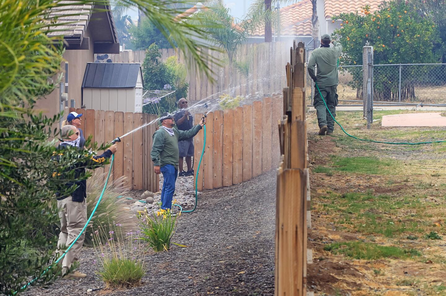 Residents water the fence of a home along Viejas View Place on Friday during a fire in Alpine, California.