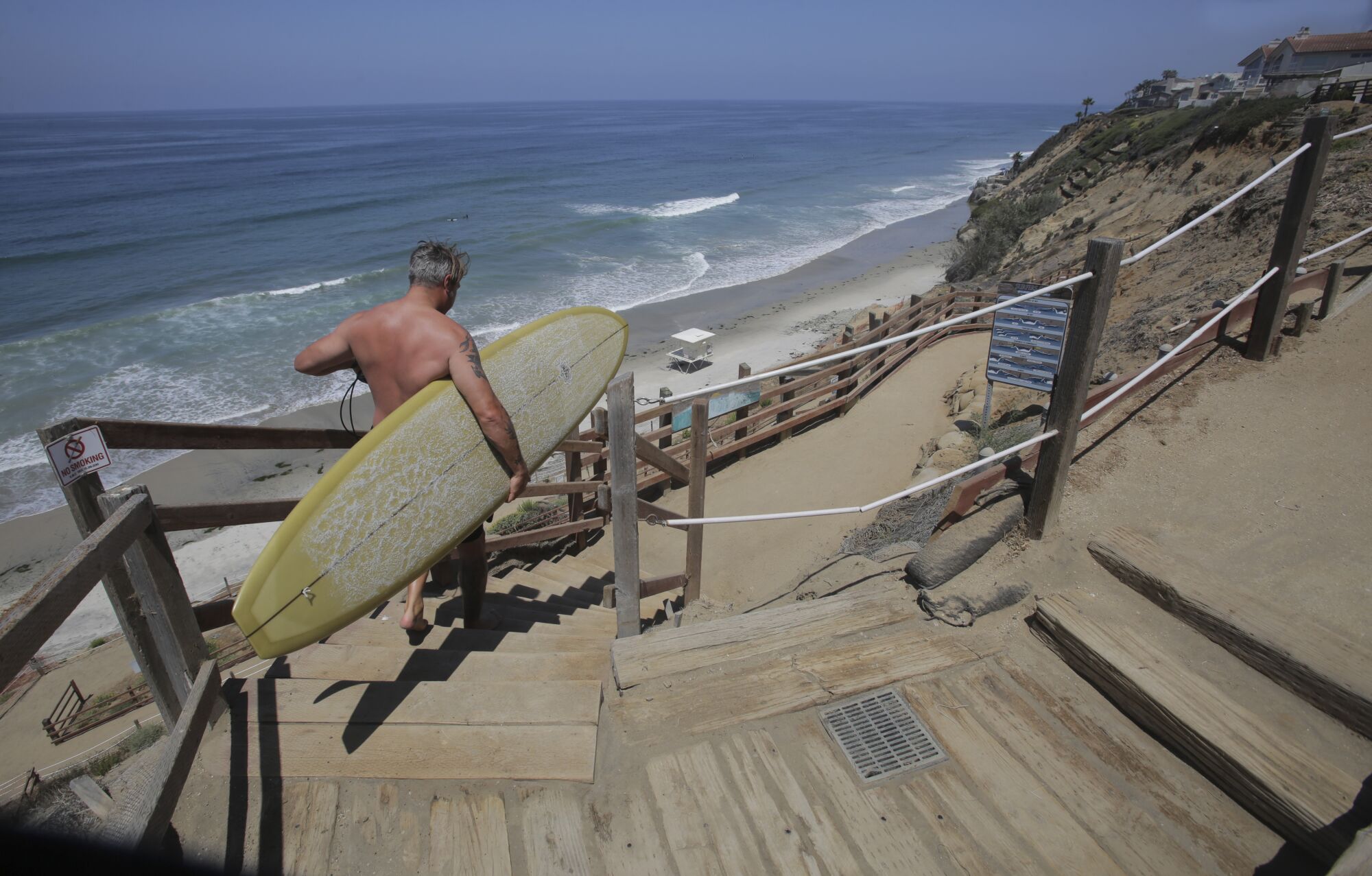 A surfer, one of the first of the day, uses the stairs down to Beacon's Beach in Encinitas, CA.
