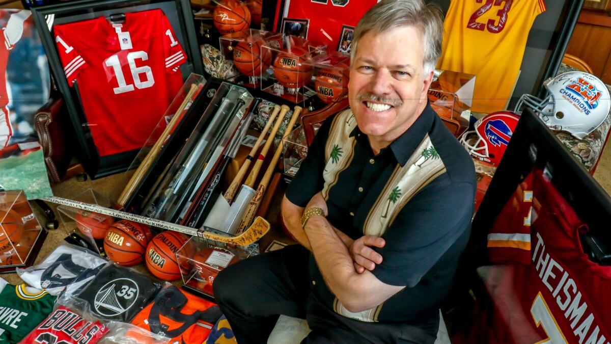 Vista resident Jeffrey D. Olsen sits with some of the 112 items of sports memorabilia he donated this past week to the Armed Forces YMCA at Camp Pendleton.