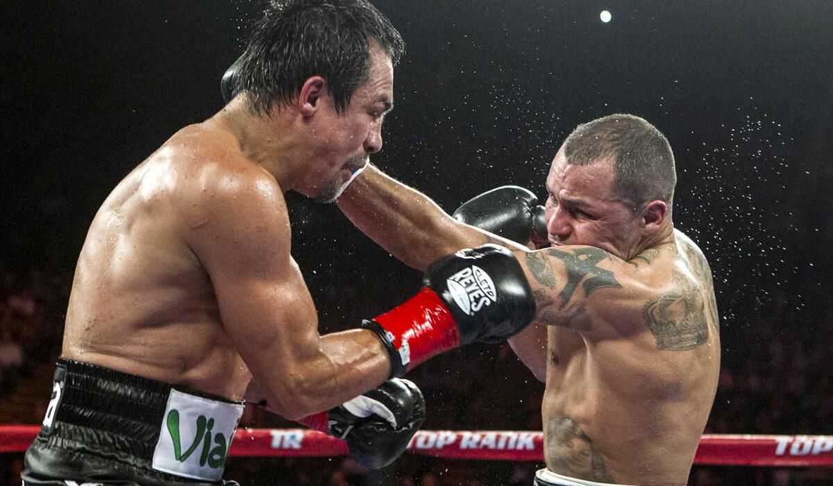 Juan Manuel Marquez, left, and Mike Alvarado exchange punches in the middle of the ring during the seventh round of a WBO welterweight title boxing match at the Forum on Saturday night.