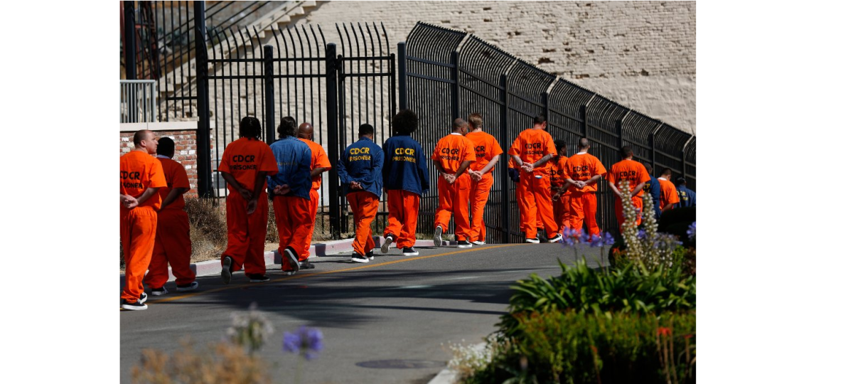 Inmates walk in file in front at San Quentin State Prison