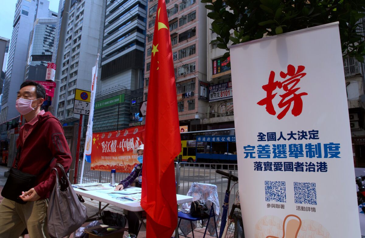 A man walks past a banner that reads "Support the proposal of National People's Congress (NPC) for the draft changes of election rules for Hong Kong" at a downtown street in Hong Kong Thursday, March 11, 2021. China's ceremonial parliament on Thursday approved a resolution to alter Hong Kong's election law that many see as effectively ending the city's already highly attenuated local democracy. (AP Photo/Vincent Yu)