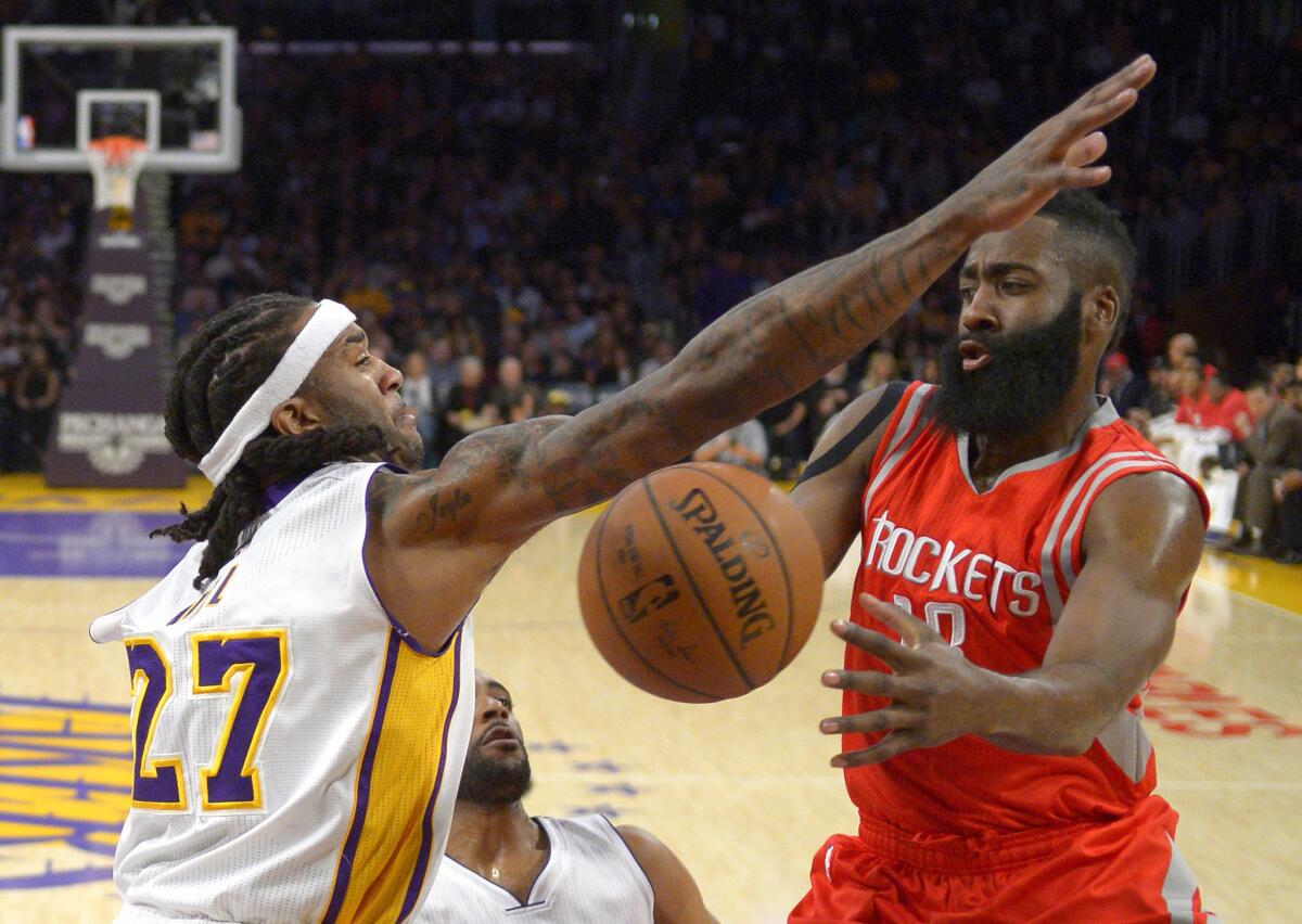 Lakers center Jordan Hill (27) forces Rockets guard James Harden to pass after driving to the basket in the first half.